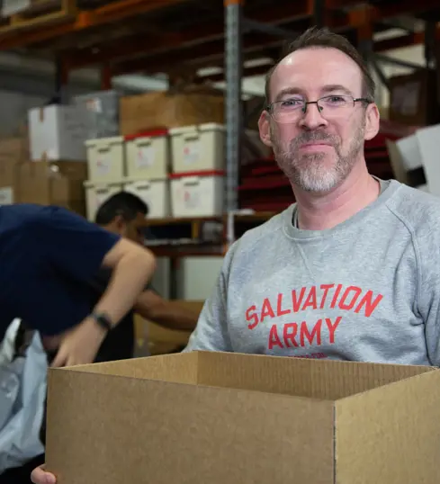 A Salvation Army volunteer carrying a box of supplies to serve the community.