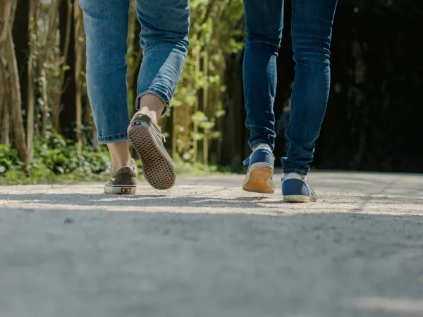Two people's legs as they walk down the street.
