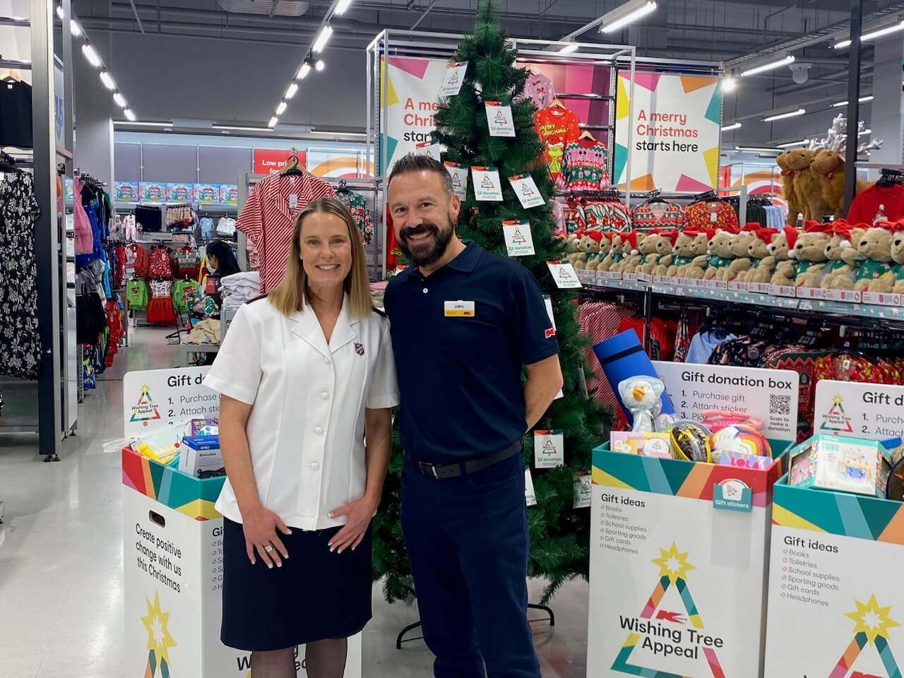 CEO John Gualtieri of Kmart stands next to a Salvos officer by the Kmart Wishing Tree boxes.