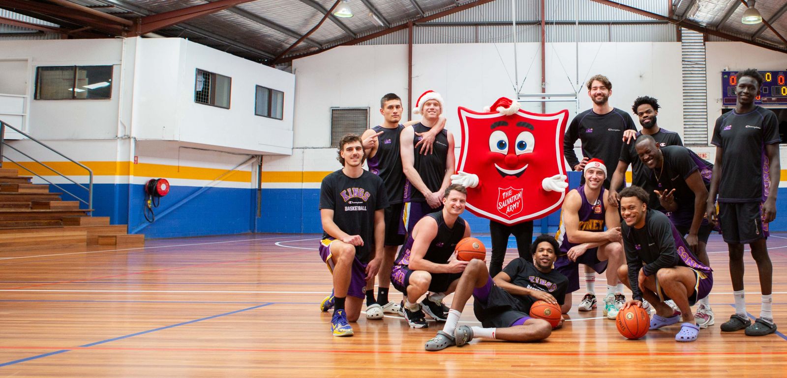 Sydney Kings players posing with Shieldy the Salvos mascot