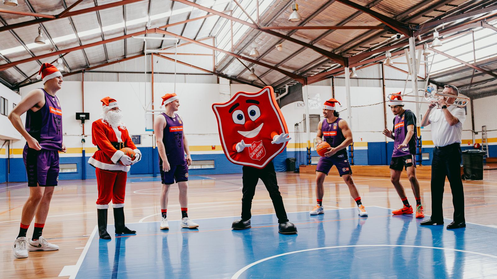 Sydney Kings players posing with Shieldy the Salvos mascot