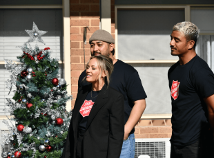 Salvation Army ambassador and singer/songwriter Samantha Jade standing outside singing a Christmas carol with two back-up singers. 
