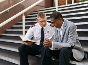 A salvos officer giving support to a man on the steps