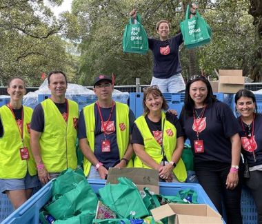 Volunteer Jason (centre, in hat) with a Salvos team packing and selling candle bags to support people who are struggling.