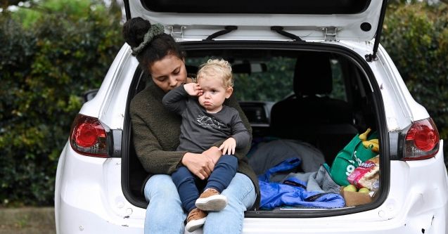 A mother and child sitting on boot of car