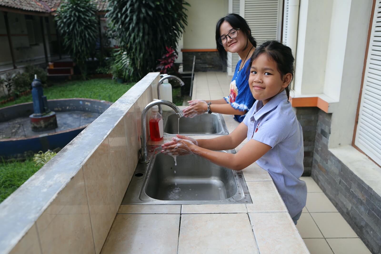 Girls using a sink to wash their hands with clean water.