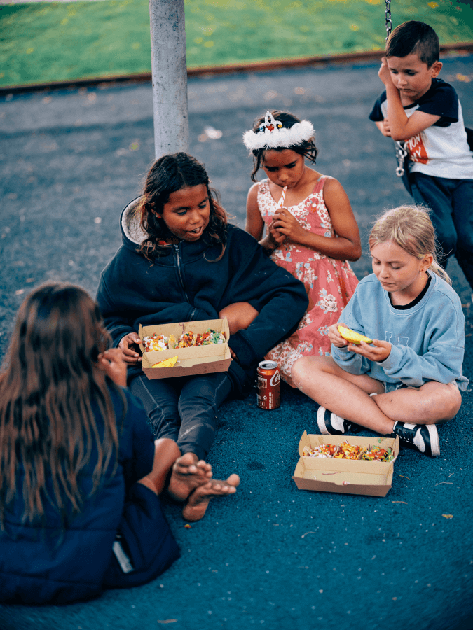 Five kids are enjoying some delicious tacos on the street and having a blast!