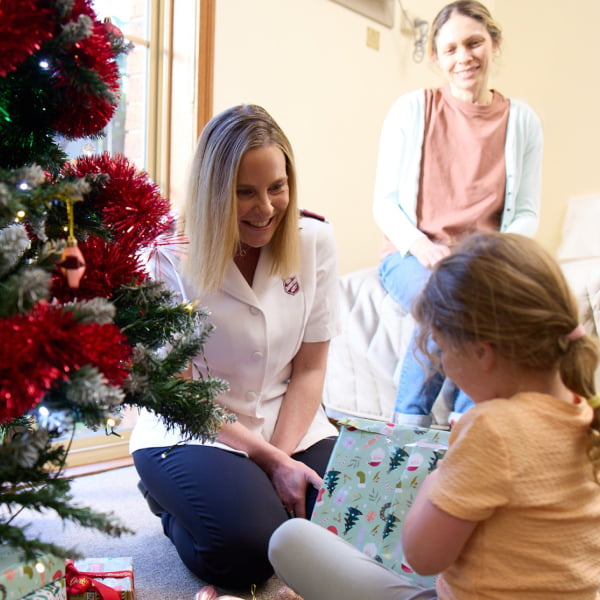 Sophie watches Taylor opening Christmas presents with a Salvos Officer.