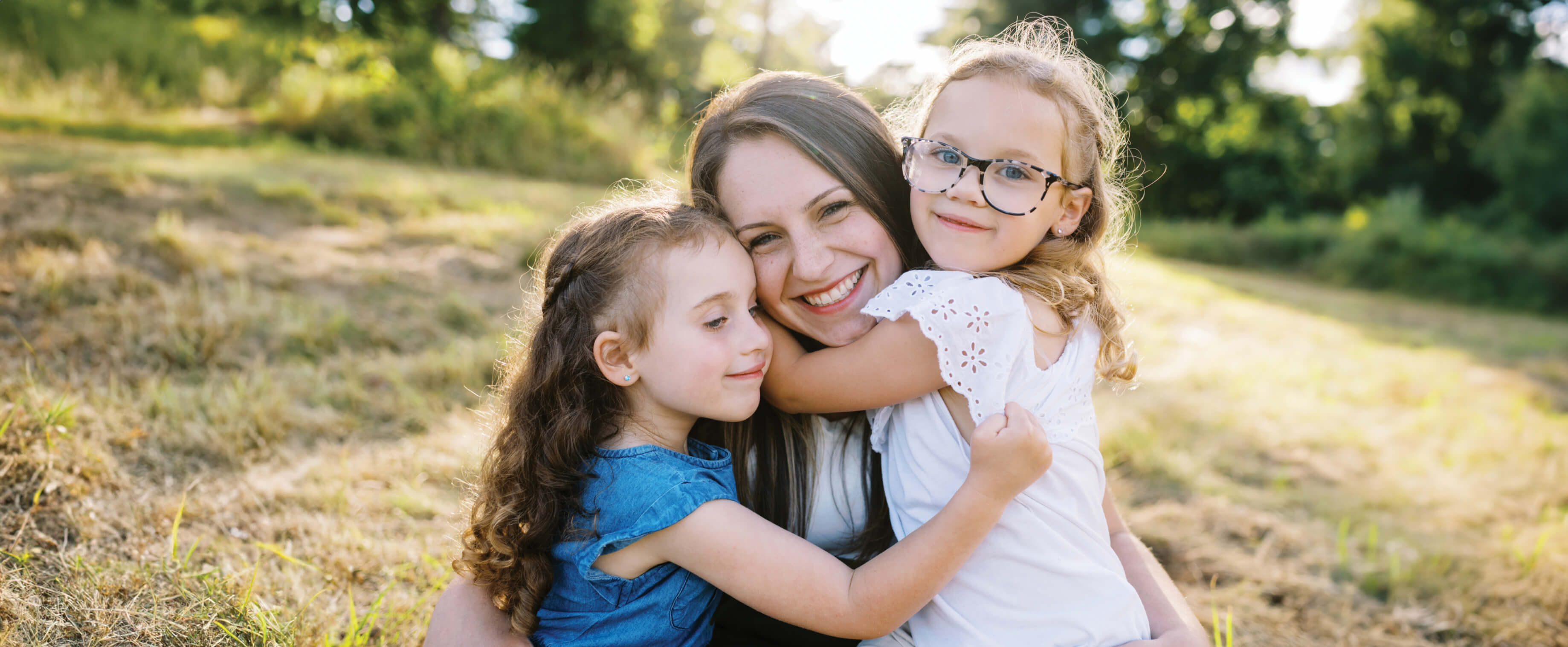 A young mother is hugged by her two daughters