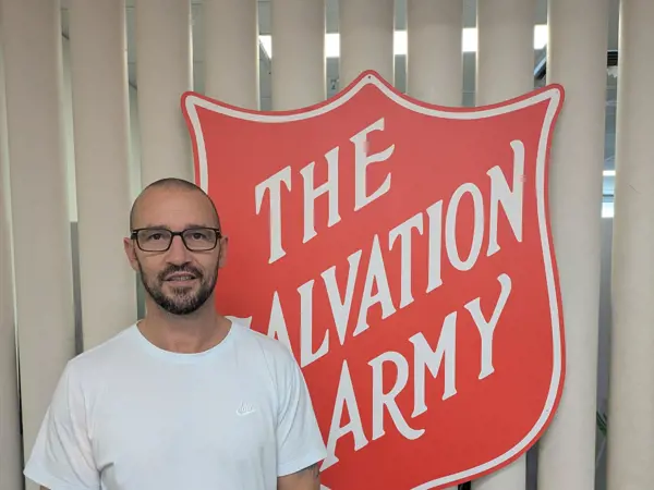 Natham standing in front of The Salvation Army shield logo.
