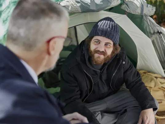 A Salvos officer talks with a young man living in a tent